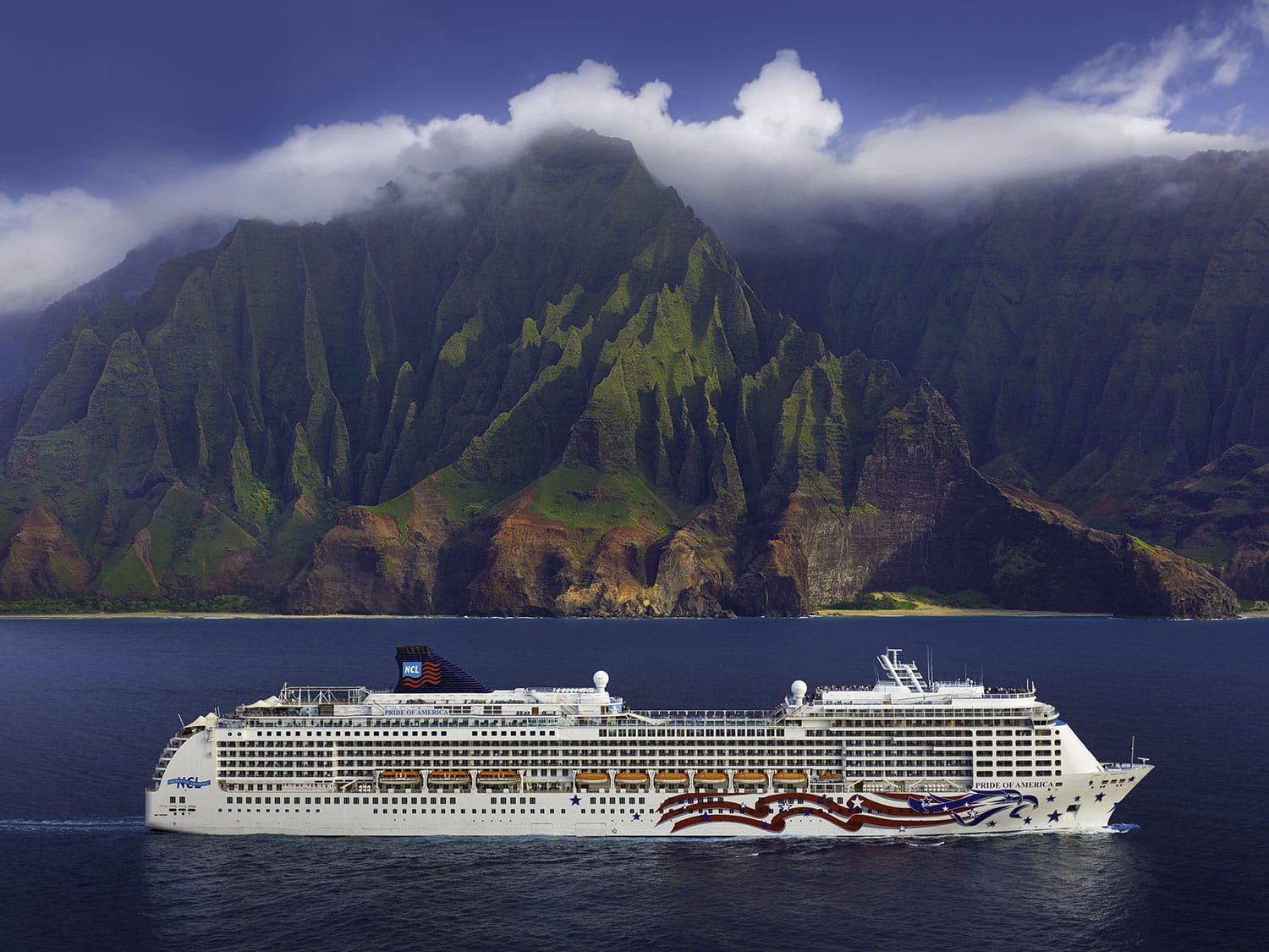 Cruiseskip fra Norwegian Cruise Line ved Hawaii med utsikt mot grønne fjell og kystlinje